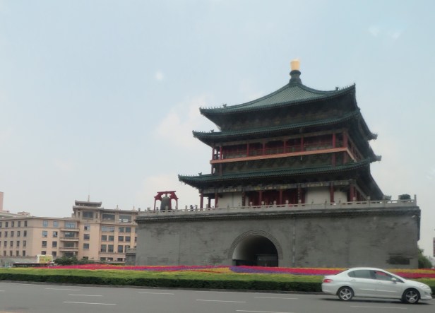 Xi’an’s Bell Tower sits surrounded by flowers and a busy traffic circle.