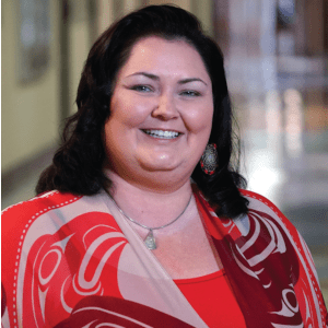 Wendy Smythe, wearing a red and tan shirt, smiles into the camera.
