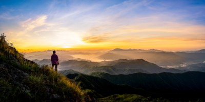 A grown woman standing on a mountain at sunrise